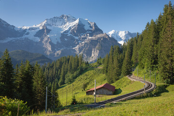 The Jungfrau paek in Bernese alps with the railway over the alps meadows.