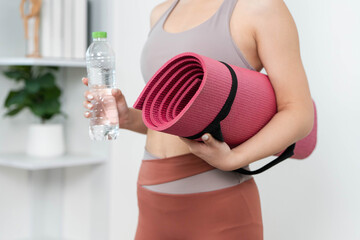 Yoga Essentials. Young woman carrying yoga mat and water bottle for workout.