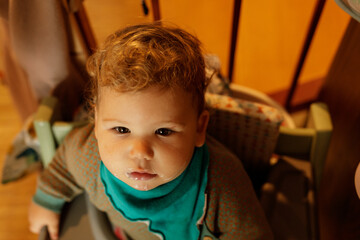 Close-up of a cute toddler with blond hair and a milk mustache, sitting in a high chair.