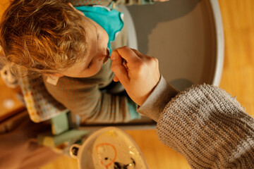 Close-up of a mother gently feeding her toddler. High-quality image perfect for blogs, articles,...