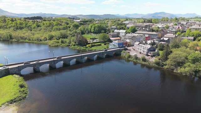 Aerial view of Killorglin, County Kerry. Calm river, stone bridge, rower gliding by charming Irish town houses. Serene and scenic Irish countryside.