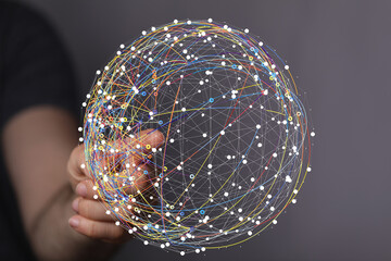 Hand interacting with a digital sphere, visualizing global network connections and data flow.