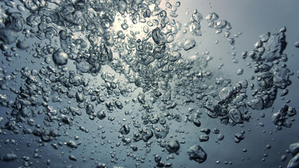 Underwater art photography. Air bubbles going towards the surface in sunlight in the deep blue sea.