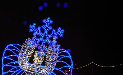 Bright blue snowflake decoration illuminates a festive night scene in a cozy winter setting