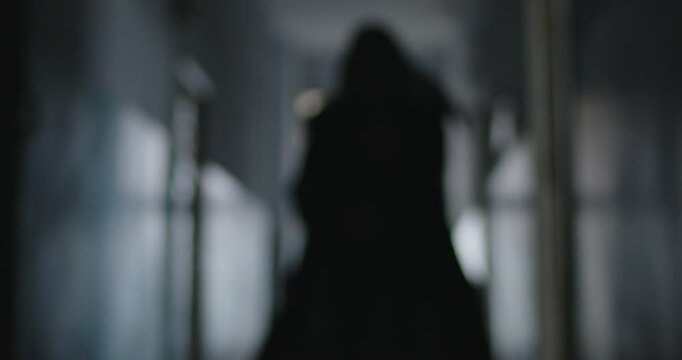Sinister black silhouette of grim reaper death quickly approaching camera, swinging his scythe. Mysterious figure dressed in hooded black cloak running at you, creating sense of fear and anxiety.