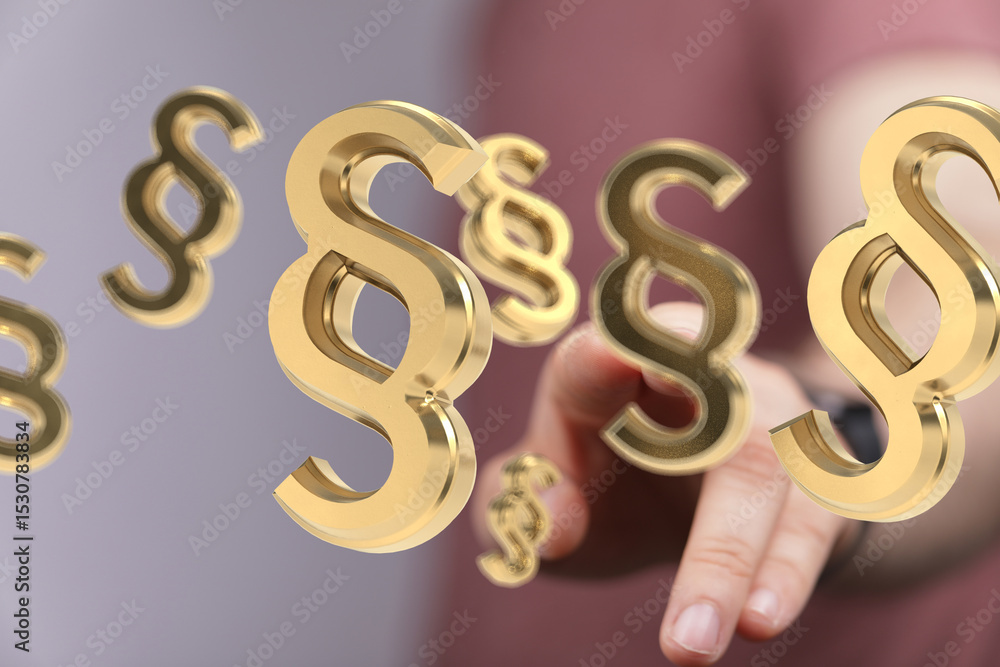 Poster Abstract image of 3D golden paragraph symbols floating towards a hand, symbolizing legal concepts.