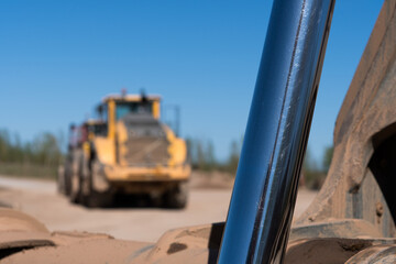 A cyclinder of a digger arm with a industrial vehicle in the background