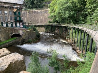 Modern curved bridge over river beside old mill