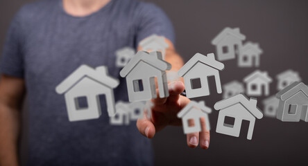 Conceptual image of a person interacting with 3D house icons, representing real estate, property,...