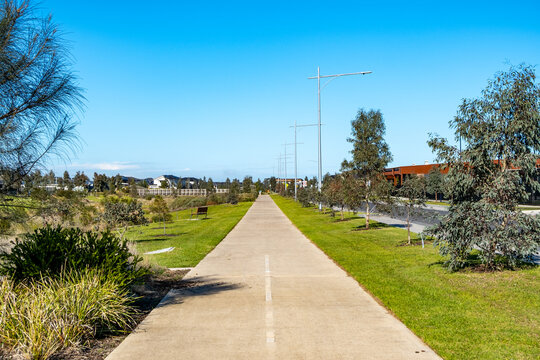 A straight, landscaped shared path designed for pedestrians and cyclists along a suburban road. Tarneit, Australia.Modern urban planning with open space, and accessible active transport infrastructure