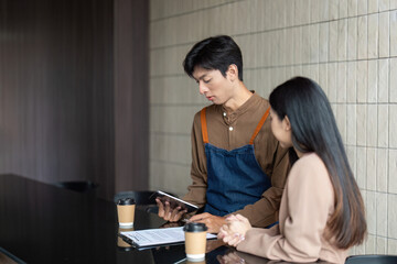 Fototapeta premium Entrepreneurial Collaboration. Young professionals reviewing plans with a tablet in a cafe.