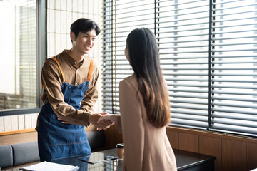 Entrepreneurial Engagement. Young professionals shaking hands in a modern workspace.