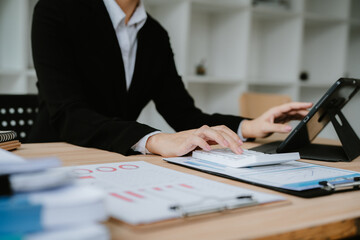 Smiling asian woman or accountant working with documents using calculator and tablet computer laptop at the office desk
