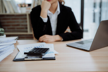 Concentrated Asian businesswoman working on laptop computer reading financial document report in office. Accountant, entrepreneur, manager. Businesswoman preparing documents using pc. Copy space.