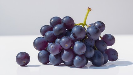 Fototapeta premium Black grapes set against a white background create a striking visual contrast. Juicy grapes are perfect for producing flavorful wines. The white background emphasizes the vivid color of the grape.
