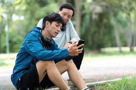 Father and Son Relaxing After Exercise. Sharing moments and technology.