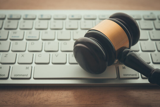 Judge hammer gavel on computer keyboard wooden table background. Online internet crime and scammer, social media law, defamation law, fake news concept.