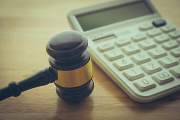 Gavel hammer judge and white calculator on wooden table background. Tax law, financial law or...