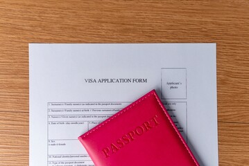 A visa application form and a red passport. International travel concept.
