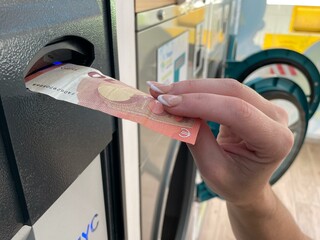 Mano insertando billete en la máquina 