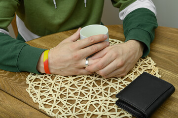 Man playing with silver wedding ring on his finger at a table in a restaurant, divorced man on a...
