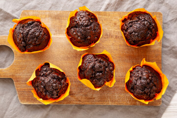 Homemade Chocolate Chip Muffins on a wooden board, top view.