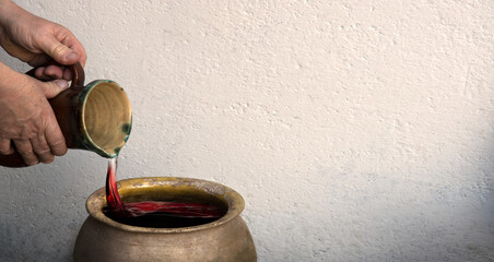A hand holds a clay jar and pours water