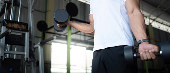 Focused Strength Training. Close-up of young man lifting dumbbells in gym.
