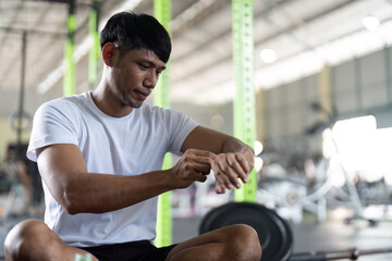 Fitness and Focus. Young man adjusting smartwatch while exercising in gym.