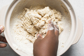 Overhead view of homemade pretzels dough being mixed in a bowl, top view of soft pretzel dough on a white background