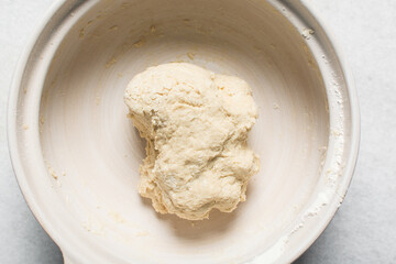 Overhead view of homemade pretzels dough being mixed in a bowl, top view of soft pretzel dough on a white background