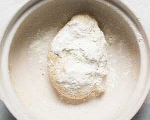 Overhead view of homemade pretzels dough being mixed in a bowl, top view of soft pretzel dough on a white background