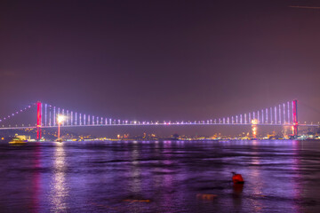 The Bosphorus Bridge (15 July Martyrs Bridge) in Istanbul illuminated with purple and red lights at...