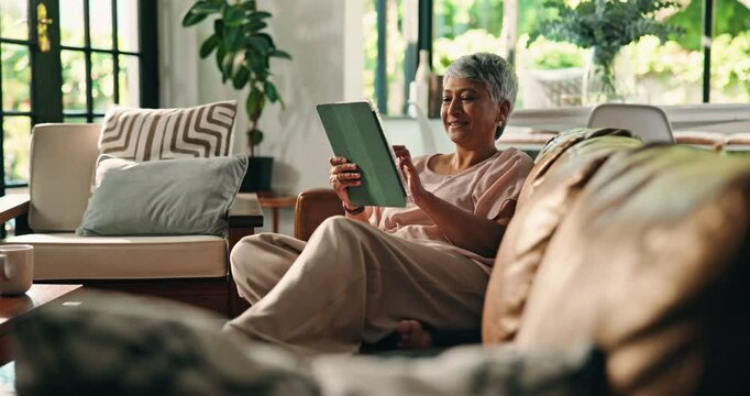 Senior woman, relax and tablet on sofa for playing online bingo, gambling app or internet surfing. Retirement, happy person and digital tech in home for gaming site, streaming subscription or ebook