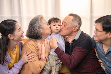 Fototapeta premium Family celebration with grandparents, parents, and child sharing affectionate moments indoors in a cozy living room