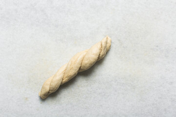 Overhead view of homemade pretzels dough being shaped on a white countertop, process of making soft pretzel