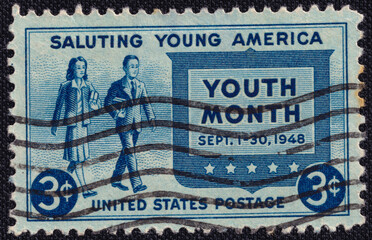A girl and a young man with books in their hands on a 1948 USA vintage postage stamp. The stamp...