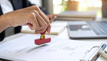 Close-up of hand using a red stamp on a legal document, indicating confirmation or validation in administrative work. business concept.