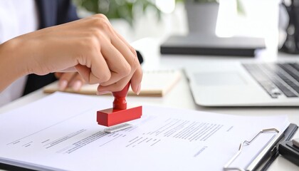 Close-up of hand using a red stamp on a legal document, indicating confirmation or validation in administrative work. business concept.