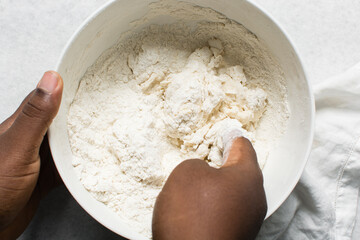 Overhead view of steamed bun dough being kneaded in a white bowl, top view of mantou dough being mixed, process of making steamed buns