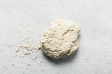 Overhead view of steamed bun dough kneaded on a white countertop, top view of mantou dough being mixed, process of making steamed buns
