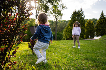 Fototapeta premium Two children enjoying a sunny day at the park with green surroundings