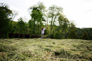 Child playing joyfully outside on a grassy field surrounded by lush trees