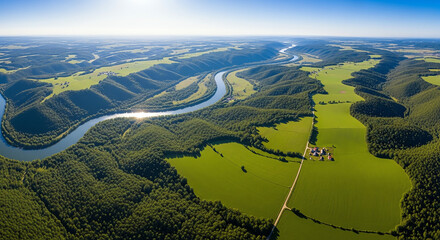Aerial view of a winding river surrounded by lush green countryside under a clear blue sky.