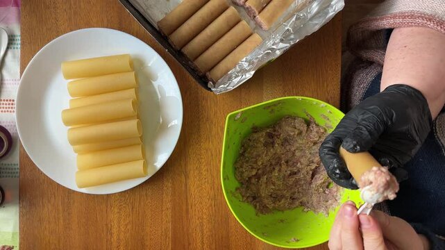 Raw cannelloni pasta during stuffing with meat filling for baking