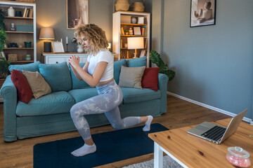 Young female student exercising at home to relieve back pain from long study hours, using online...