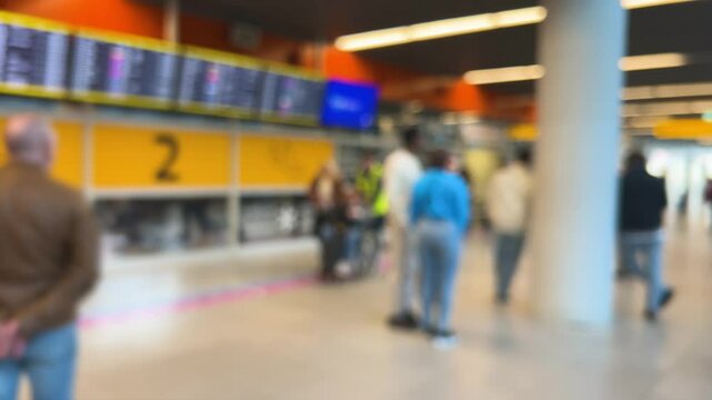 People waiting to greet passengers stand at arrival gate 2 at Warsaw Chopin Airport (WAW), Poland. Passengers arriving by plane exit with their luggage. Out of focus.