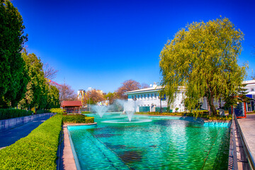 Bright and clear day in Ankara park featuring turquoise water fountains, lush greenery, walking...