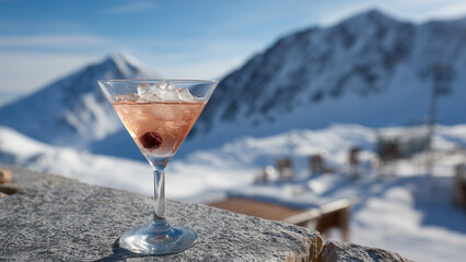 A single cocktail in an inverted cone-shaped glass sits elegantly against a breathtaking backdrop of snow-covered mountains, blending refined refreshment with stunning alpine scenery and serenity.