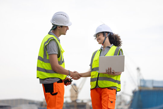 Young Industrial Workers Shaking Hands at a Port, Port Engineers Discussing Logistics at a Shipping Yard, Team of Maritime Professionals Planning at a Harbor